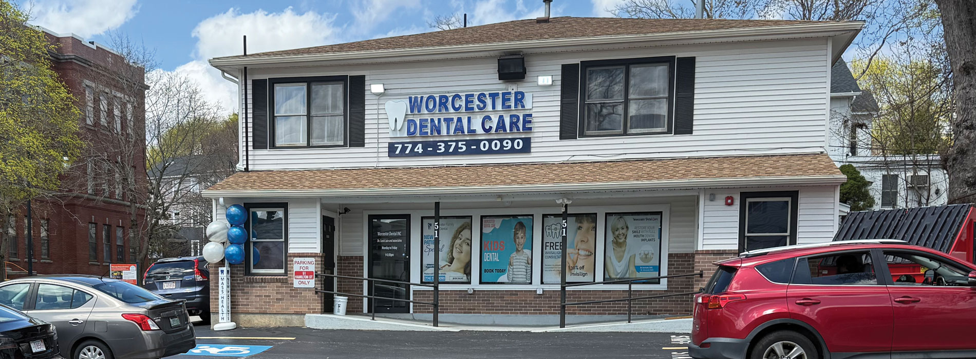The image shows a building with a sign that reads  WORCESTER DENTAL  and a parking lot with cars parked outside of the building.